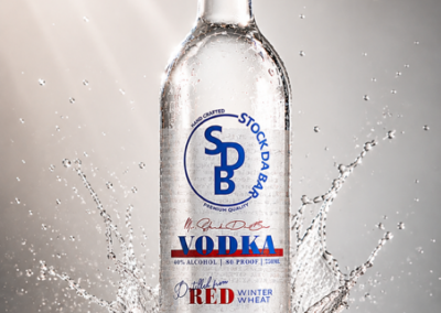 Clear vodka bottle with red cap splashing water around it; label shows 'VODKA' and 'Made in Michigan' for a promotional shot.